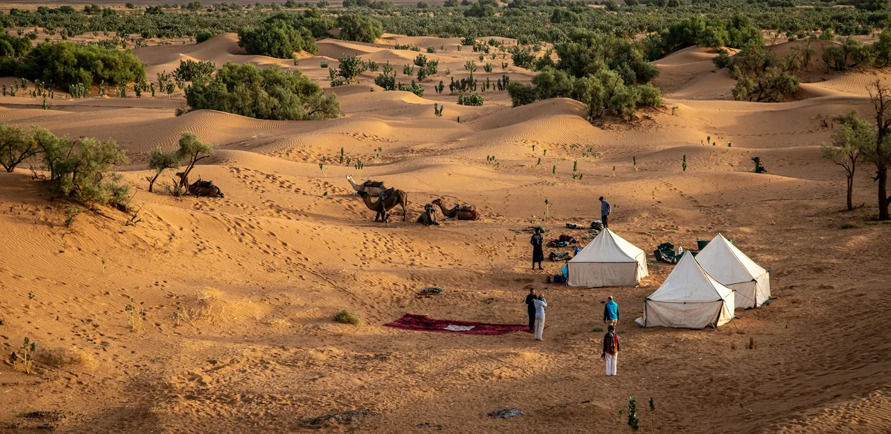 Desert campsite with tents and people at sunset